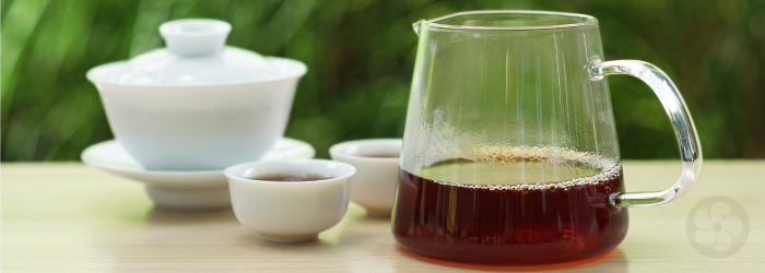 dark, reddish Keemun in a glass server with a white porcelain gaiwan